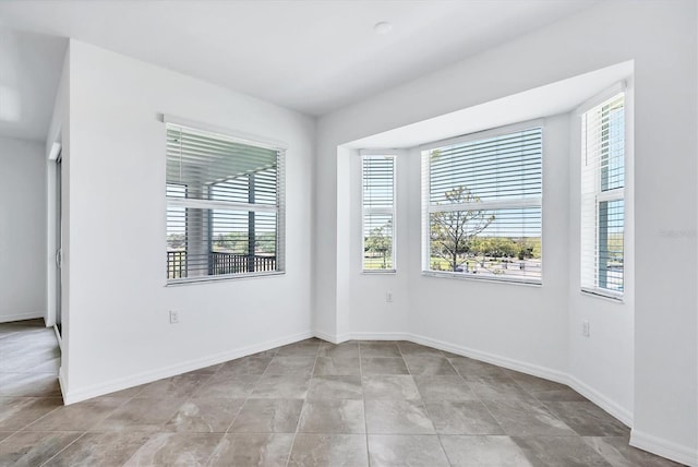 spare room featuring a wealth of natural light and baseboards