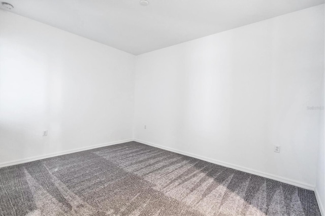 empty room with dark carpet and baseboards