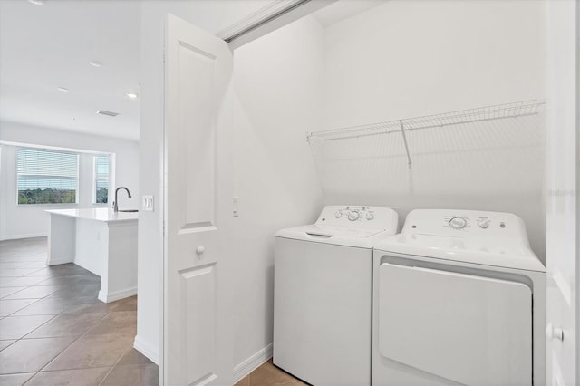 laundry room featuring a sink, washing machine and dryer, light tile patterned flooring, baseboards, and laundry area