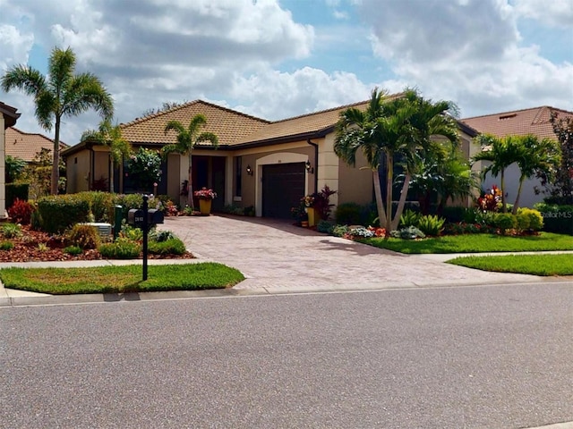 view of front of home featuring decorative driveway, a garage, stucco siding, and a tile roof