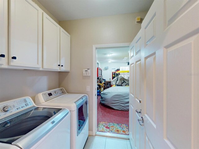 washroom featuring light tile patterned floors, cabinet space, and separate washer and dryer