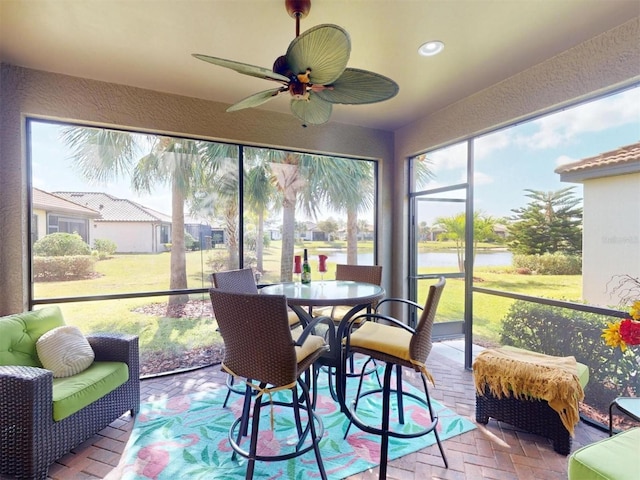 sunroom featuring a ceiling fan and a water view