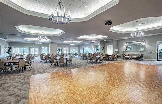 interior space with a chandelier, baseboards, a tray ceiling, and ornamental molding