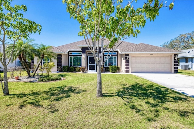 view of front of home featuring a front yard, central AC unit, stucco siding, a garage, and driveway