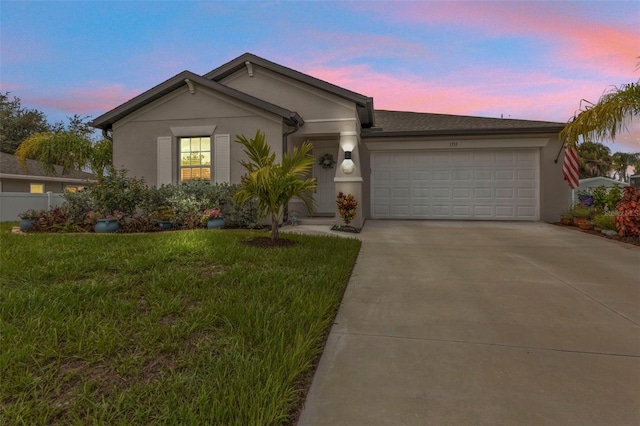 ranch-style house with stucco siding, concrete driveway, a lawn, and a garage