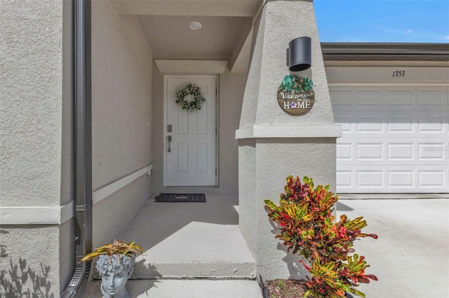 property entrance featuring a garage and stucco siding