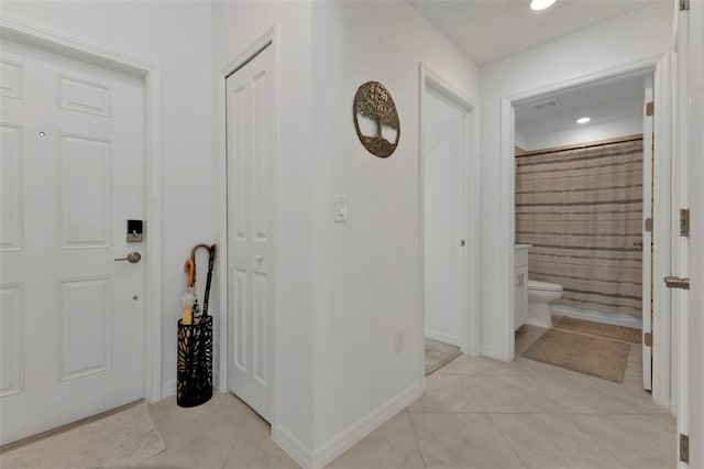 hallway with light tile patterned floors, visible vents, recessed lighting, and baseboards