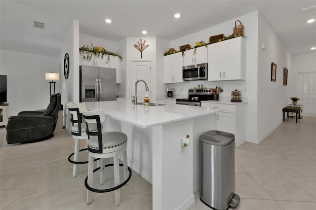 kitchen with a sink, a kitchen breakfast bar, visible vents, and stainless steel appliances