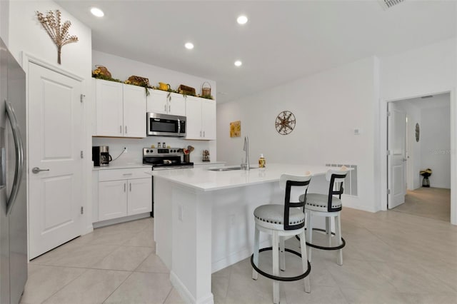 kitchen featuring a center island with sink, visible vents, a sink, stainless steel appliances, and white cabinets