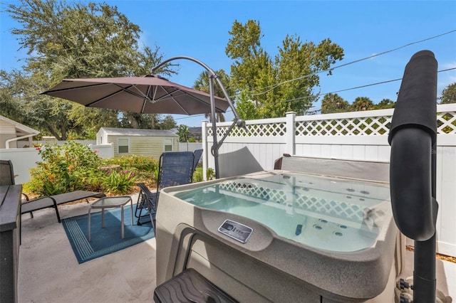 view of patio with a hot tub, a storage shed, an outdoor structure, and fence