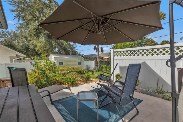 view of patio / terrace with outdoor dining area, a fenced backyard, and an outdoor structure