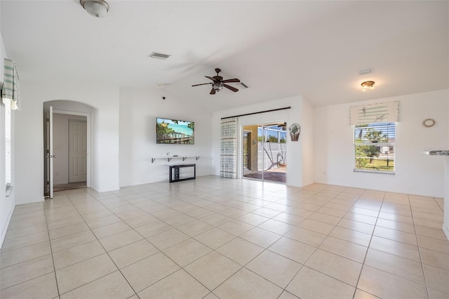 unfurnished living room featuring visible vents, arched walkways, a healthy amount of sunlight, and light tile patterned flooring