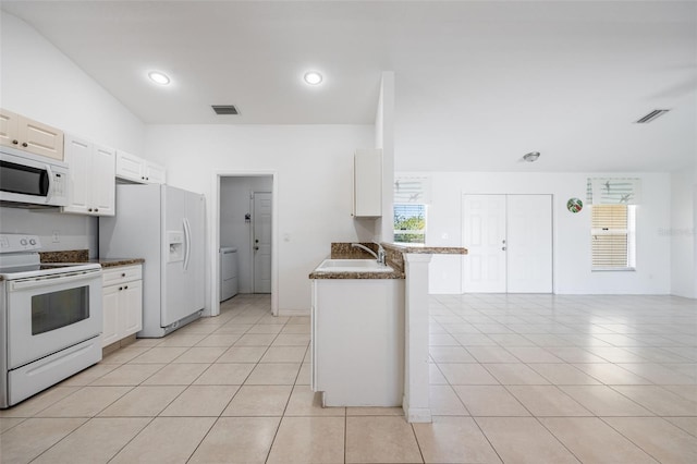 kitchen with visible vents, a sink, white appliances, light tile patterned floors, and washer / dryer