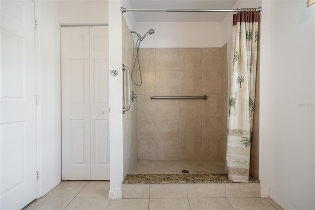 bathroom with tile patterned flooring, baseboards, a closet, and a tile shower