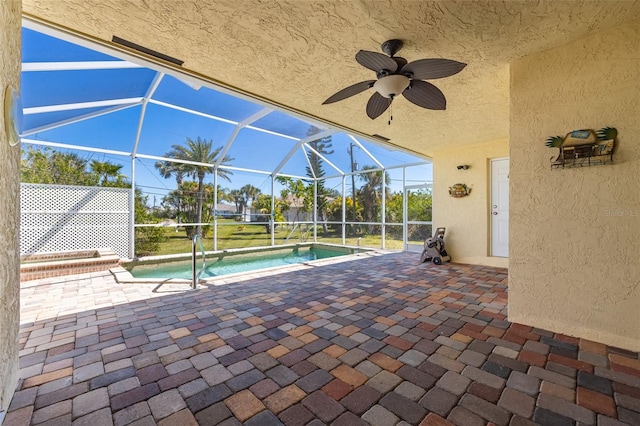 outdoor pool featuring glass enclosure, ceiling fan, and a patio area