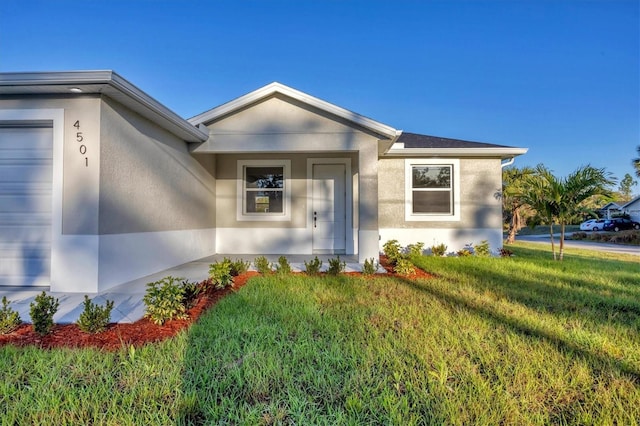 view of front of property featuring stucco siding, an attached garage, and a front yard