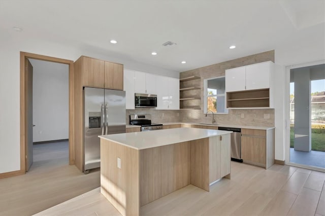 kitchen featuring a healthy amount of sunlight, a kitchen island, open shelves, a sink, and stainless steel appliances