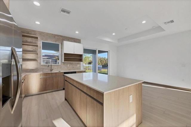 kitchen with visible vents, open shelves, a center island, stainless steel fridge, and a raised ceiling