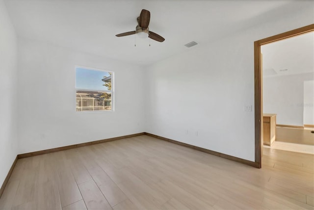 empty room with ceiling fan, visible vents, baseboards, and wood finished floors