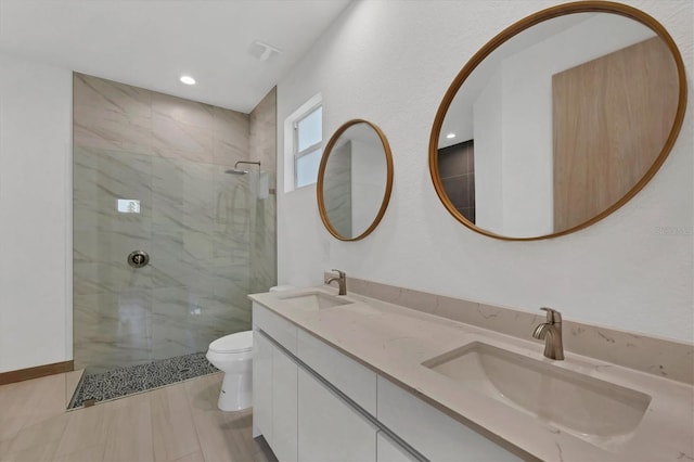 bathroom featuring toilet, a tile shower, and a sink