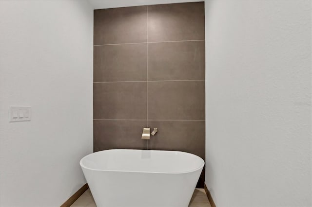 bathroom with a soaking tub and baseboards