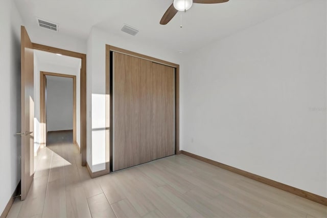 unfurnished bedroom featuring light wood-style flooring, baseboards, visible vents, and a closet