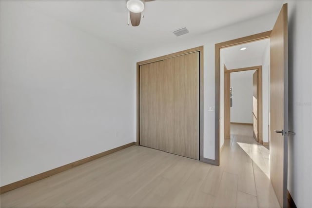 unfurnished bedroom with light wood finished floors, visible vents, ceiling fan, baseboards, and a closet