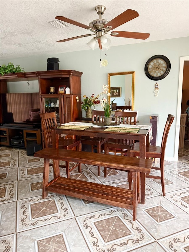 dining room featuring light tile patterned floors, visible vents, a textured ceiling, and a ceiling fan