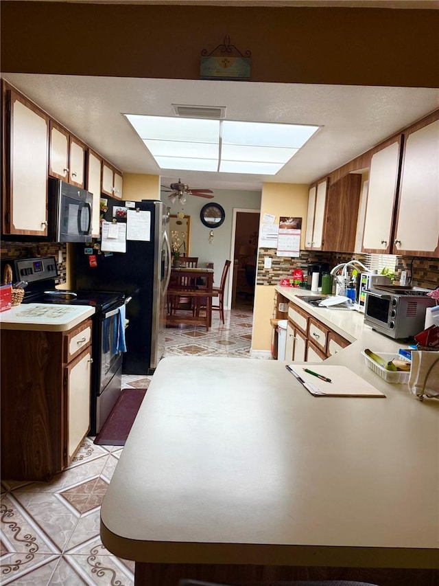 kitchen with tasteful backsplash, appliances with stainless steel finishes, light countertops, and a sink