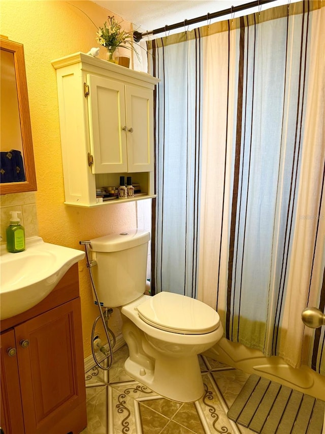 full bathroom featuring tile patterned floors, toilet, vanity, and a textured wall