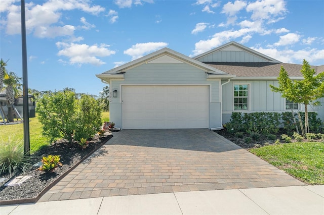 ranch-style home featuring a garage, a front yard, decorative driveway, and board and batten siding