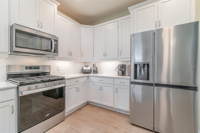 kitchen with wood tiled floor, stainless steel appliances, light countertops, white cabinets, and tasteful backsplash