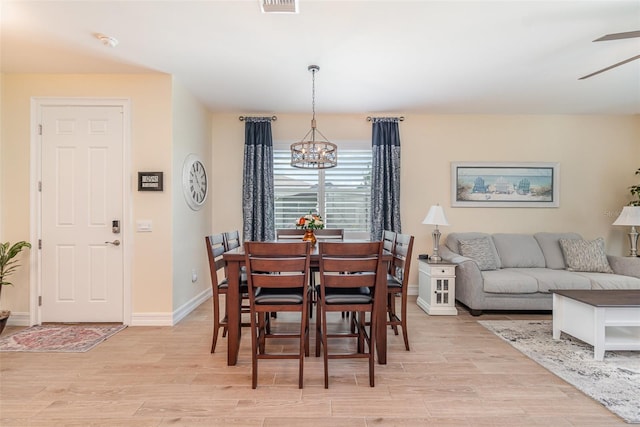 dining area with baseboards, ceiling fan with notable chandelier, visible vents, and light wood finished floors