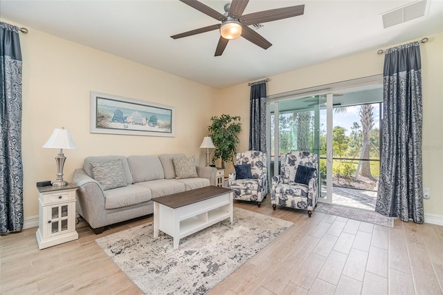 living room featuring visible vents, baseboards, light wood-type flooring, and ceiling fan