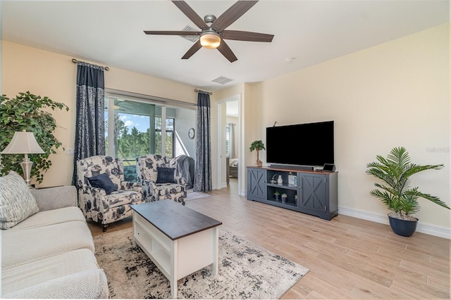 living room featuring ceiling fan, light wood-style floors, visible vents, and baseboards