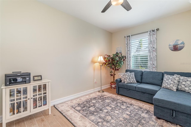 living area featuring a ceiling fan, wood finished floors, and baseboards