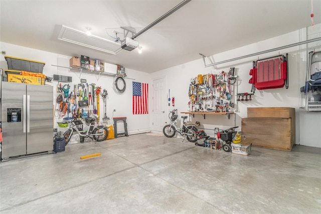 garage with a workshop area, a garage door opener, stainless steel fridge with ice dispenser, and bike storage