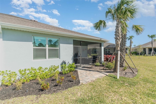 back of property featuring a yard, a sunroom, and stucco siding