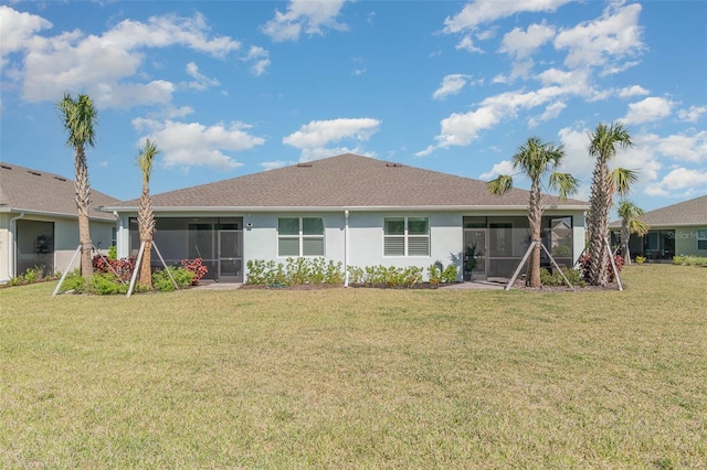 rear view of house featuring stucco siding, a lawn, and a sunroom