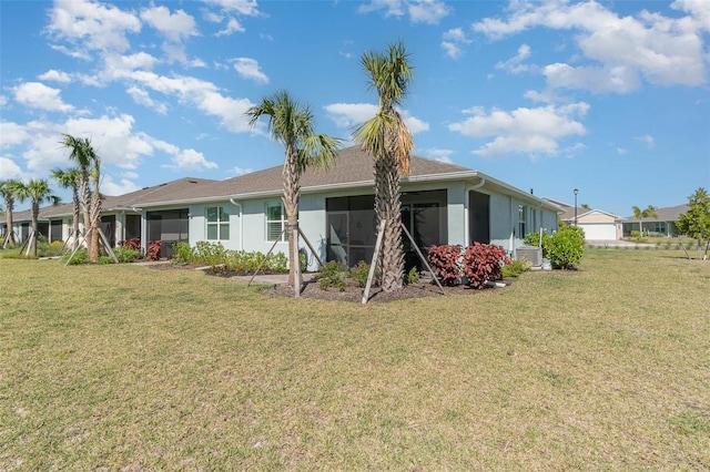 back of property with stucco siding, a lawn, and a sunroom