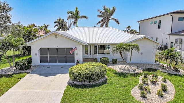 view of front facade featuring a garage, metal roof, concrete driveway, and a front yard