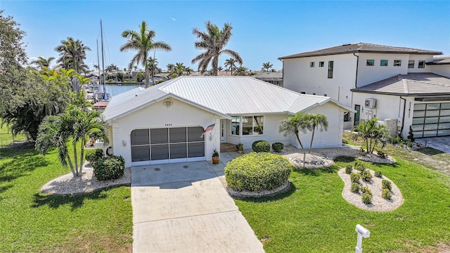 view of front of property with metal roof, driveway, a front yard, and an attached garage