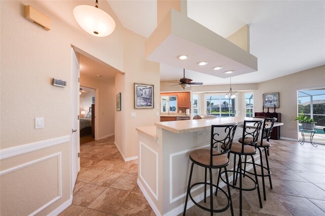 kitchen featuring a ceiling fan, a breakfast bar, recessed lighting, light countertops, and pendant lighting