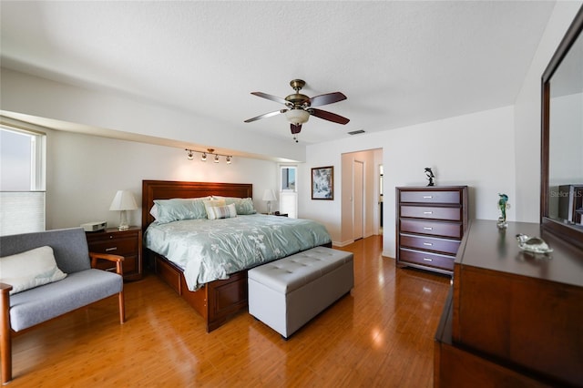 bedroom with light wood-type flooring, visible vents, and a ceiling fan