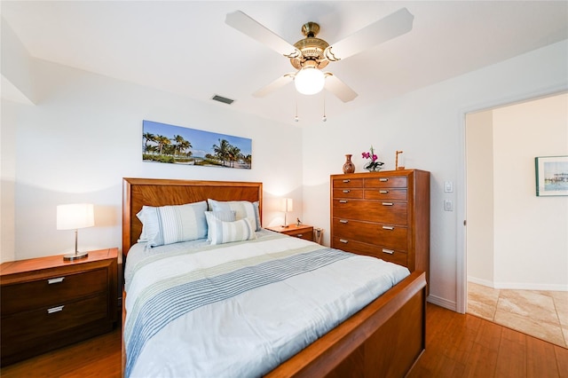 bedroom featuring visible vents, baseboards, ceiling fan, and wood finished floors