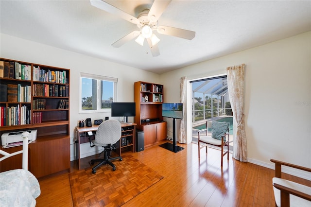 office space with parquet flooring, a ceiling fan, and baseboards