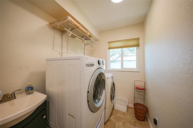 washroom featuring a sink, washing machine and dryer, laundry area, and a textured wall