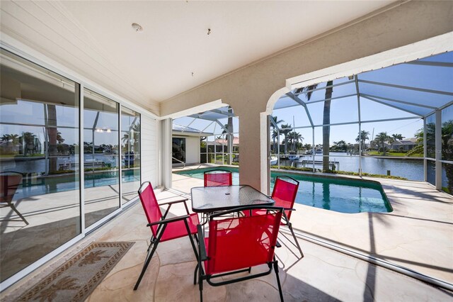 outdoor pool with glass enclosure, a patio, and a water view