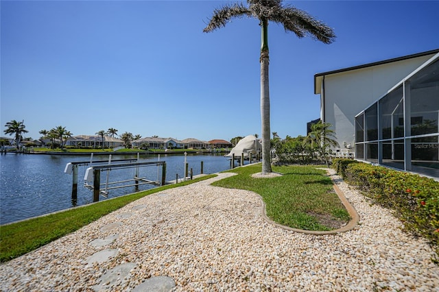 view of yard with a residential view, a water view, boat lift, and a boat dock