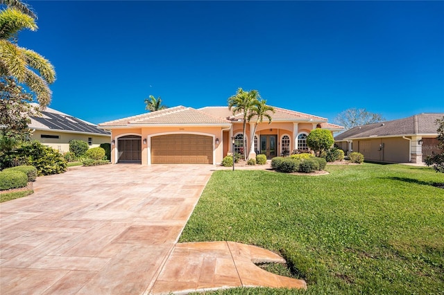 mediterranean / spanish home featuring a front yard, driveway, stucco siding, a garage, and a tile roof